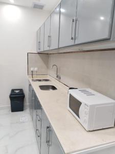 une cuisine avec évier et four micro-ondes sur un comptoir dans l'établissement هوتيل نجران للشقق الفندقية, à Najran