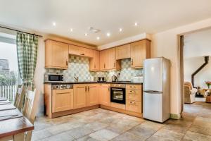 a kitchen with wooden cabinets and a white refrigerator at No 2 The Stables in Llangefni