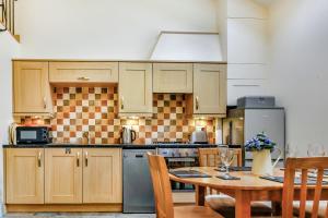 a kitchen with wooden cabinets and a table with chairs at No 4 The Shippon in Llangefni