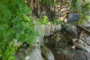 un muro di pietra con una panca e alcune piante di Arima Onsen Takayamaso Hanano a Kobe