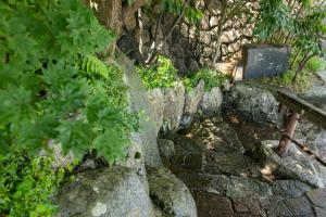 a stone wall with a bench and some plants at Arima Onsen Takayamaso Hanano in Kobe