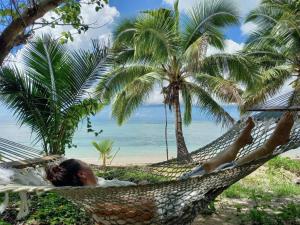 una donna sdraiata su un'amaca in spiaggia di Wai Makare Homestay a Naviti Island