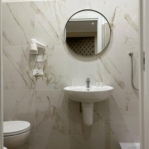 a bathroom with a sink and a mirror and a toilet at NLM Boutique Suites in Rome