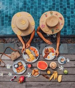 duas pessoas em chapéus de palha com pratos de comida numa piscina em Flower Boutique Hotel em Da Nang
