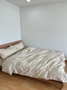 - un lit avec des draps et des oreillers blancs dans l'établissement 1 Minute house from Hongdae, à Séoul