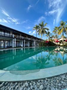 a swimming pool in front of a resort with palm trees at Palm Garden Ayurveda Resort in Ahangama