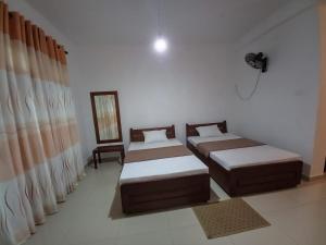 um quarto com 2 camas e um espelho em Ella gama village guest house em Diyatalawa