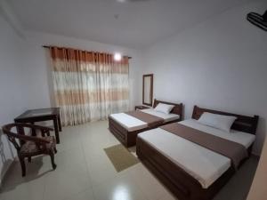 um quarto com 2 camas, uma mesa e uma cadeira em Ella gama village guest house em Diyatalawa