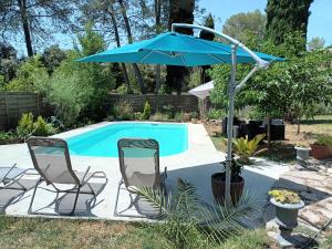dos sillas y una sombrilla junto a una piscina en Gîte 4 places St Bauzille de Montmel, en Saint-Bauzille-de-Montmel