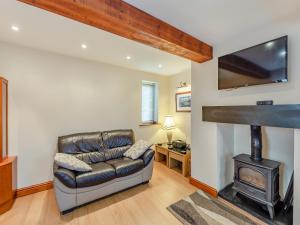 a living room with a leather couch and a fireplace at Stewner Bank Cottage in Ulverston