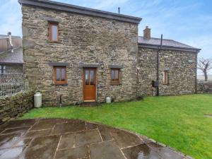 an old stone house with a grass yard in front of it at Stewner Bank Cottage in Ulverston