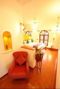 a bedroom with a bed and a chair in a room at Marari Beach Bungalow in Mararikulam