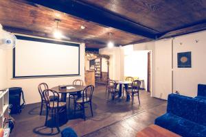 Guest House Waya في سابورو: غرفة بطاولات وكراسي وشاشة كبيرة