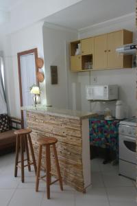 a kitchen with a counter and two stools in it at Apartamento Casa da Praia in Cabo Frio