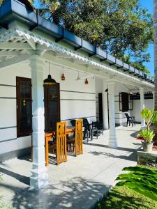 a patio with wooden chairs and a table at Oshi villa in Unawatuna