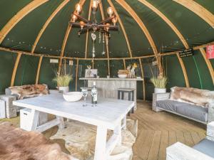 a table in a yurt with a couch and chairs at Bonnie's Shepherds Hut in Nottingham