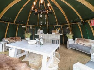 a table in a yurt with a couch and chairs at Herbie's Shepherds Hut in Nottingham