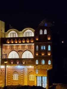 a building with arches and windows at night at Laila Flat in Al Aqālitah