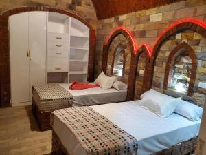two beds in a room with brick walls and arches at Laila Flat in Al Aqālitah