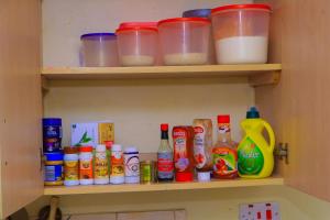 un estante lleno de botellas y recipientes de alimentos en Cool & Calm Home, en Homa Bay