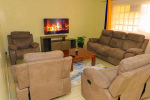 een woonkamer met een bank en stoelen en een tv bij Cool & Calm Home in Homa Bay
