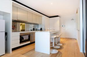 une cuisine avec des armoires blanches et un comptoir avec des tabourets dans l'établissement 2BR CBD pad, city views, free parking, pool, gym, à Melbourne