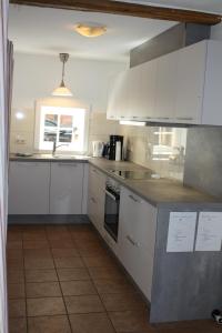 a kitchen with white cabinets and a window at Cottage - Artland's Home - Landhaus für Familien und Gruppen in Badbergen +15 photos