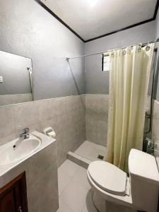 a bathroom with a toilet and a sink and a shower at Zara's Casa Rental in Siquijor