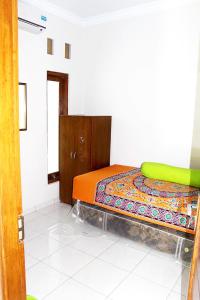 a bedroom with a bed and a green chair at Maguwoharjo Street Homestay Jogja in Seturan