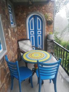 una mesa y sillas en un balcón con puerta azul en The black stone, en Ella