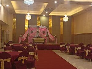 un salón de banquetes con un escenario con mesas y sillas rojas en Hotel Prakash International, en Heṭauḍā