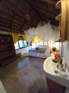 um quarto com uma cama e um lavatório num quarto em Casa Camaleao Gekko Cottadge em Praia do Tofo