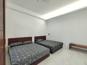 - 2 lits dans une chambre aux murs blancs dans l'établissement Nanyang Homestay 3 rooms 10 pax- Ground Floor, à Sibu