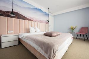 a bedroom with a large bed with a painting on the wall at Vila Sarisa in Deva
