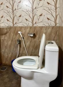 a white toilet in a bathroom with a wall at Chidambaram Spiritual Stay in Chidambaram