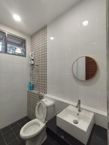La salle de bains est pourvue de toilettes, d'un lavabo et d'un miroir. dans l'établissement Nanyang Homestay 3 rooms 10 pax- Ground Floor, à Sibu