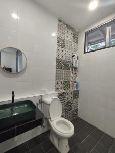 y baño con aseo, lavabo y espejo. en Nanyang Homestay 3 rooms 10 pax- Ground Floor en Sibu