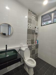 a bathroom with a toilet and a sink and a mirror at Nanyang Homestay 3 rooms 10 pax- Ground Floor in Sibu