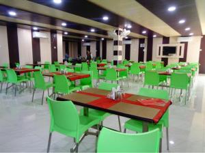 a dining room with green tables and chairs at Hotel Glory Grand, Rajgir in Rājgīr