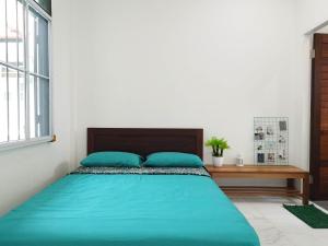 Un dormitorio con una cama con almohadas azules y una mesa. en Nanyang Homestay 3 rooms 10 pax- Ground Floor en Sibu