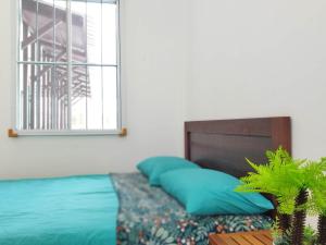 - un lit avec des oreillers bleus à côté d'une fenêtre dans l'établissement Nanyang Homestay 3 rooms 10 pax- Ground Floor, à Sibu