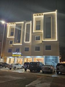 un grand bâtiment avec des voitures garées dans un parking dans l'établissement فندق زوايا الماسية فرع الحزام, à Médine