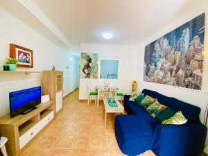 a living room with a blue couch and a tv at SaVoa 247 in Tarajalejo