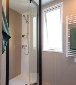 y baño con ducha de cristal y ventana. en A Casa Mia Plage, en Hermanville-sur-Mer