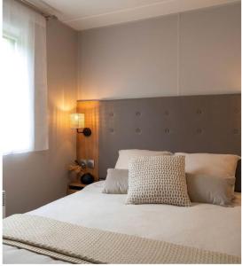 a bedroom with a large white bed with a headboard at A Casa Mia Plage in Hermanville-sur-Mer