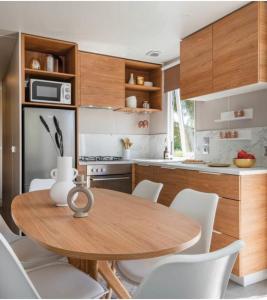 cocina con mesa de madera y sillas blancas en A Casa Mia Plage, en Hermanville-sur-Mer