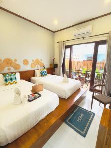 a hotel room with two beds and a balcony at Luang Prabang Museum Inn & Travel in Luang Prabang