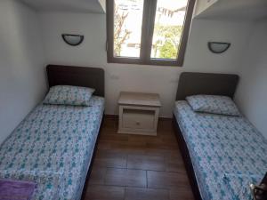 two beds in a room with a table and two windows at Villa Ivan in Risan