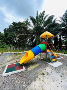 einen Spielplatz mit Rutsche und Sonnenschirm in der Unterkunft Homestay/Bilik Teluk Gading in Kuala Rompin
