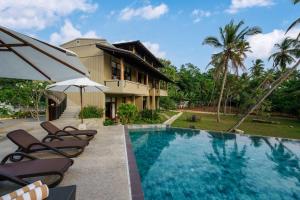 a house with a swimming pool with chairs and an umbrella at Kiss Blossom in Mirissa